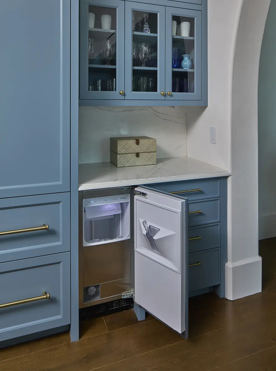 Kitchen area with blue cabinetry, stone countertop, refrigerator, and decorative box on the counter.