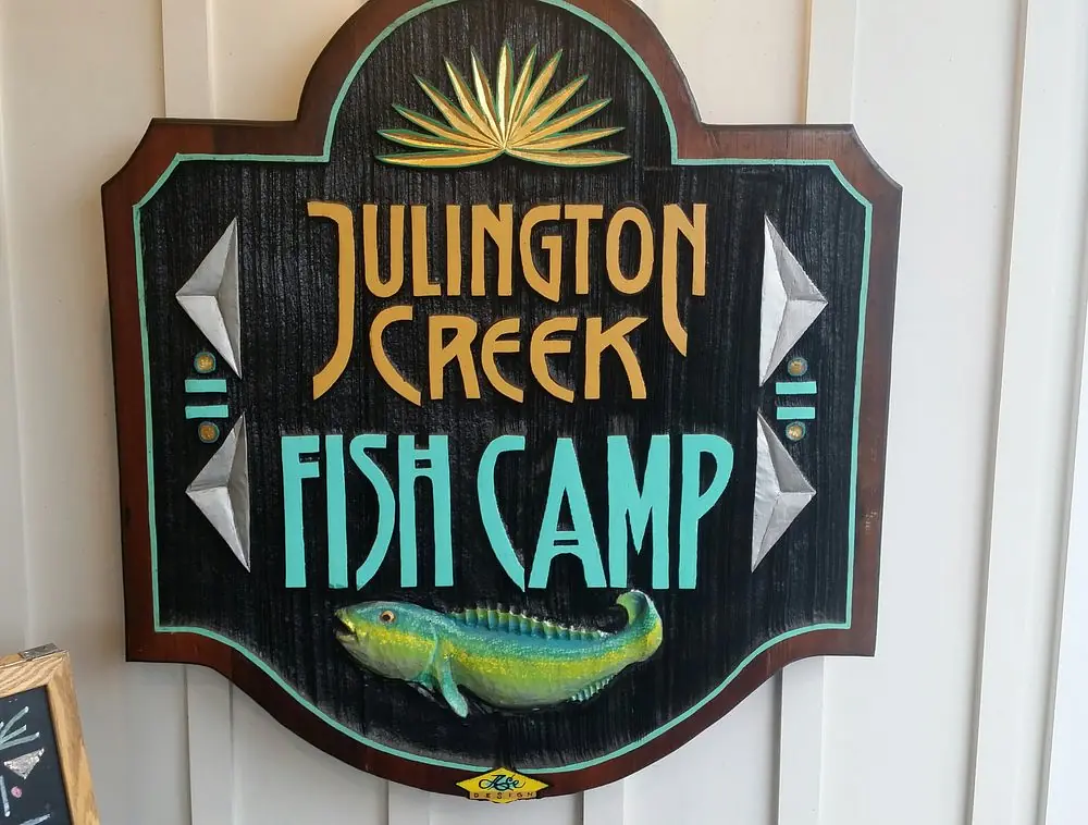 Wooden sign with 'Julington Creek Fish Camp' text, fish illustration, and decorative elements