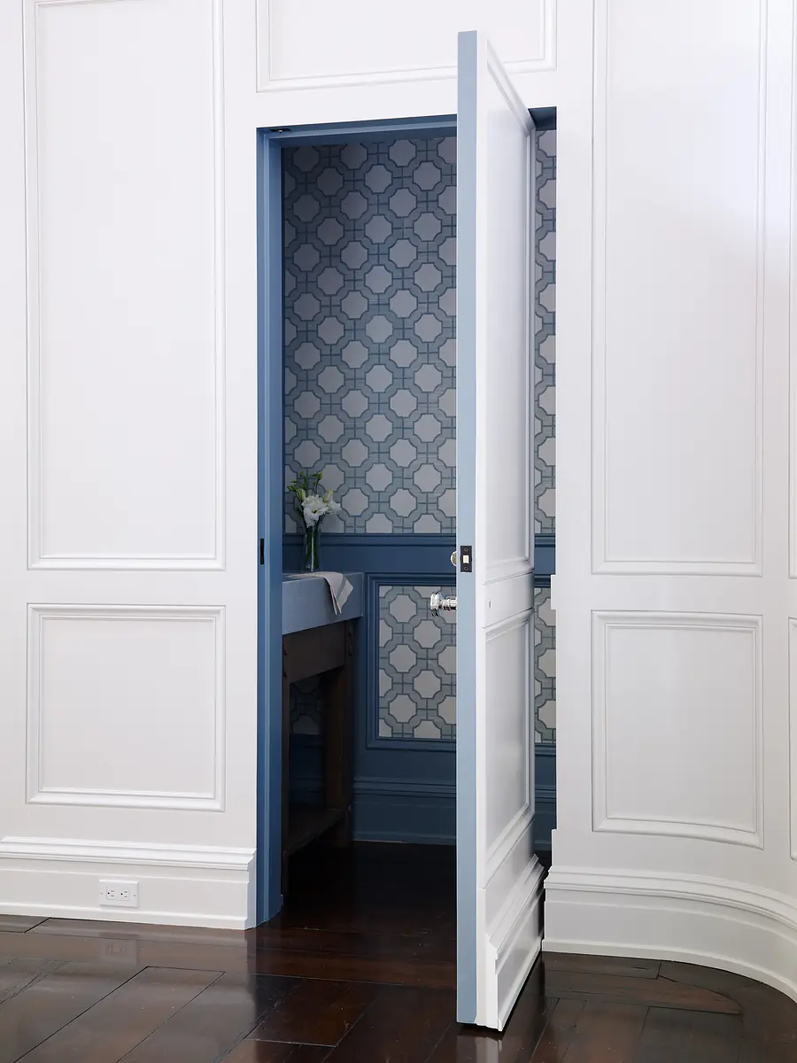 Powder room with patterned wallpaper, wooden washstand, sink, and dark wood floor