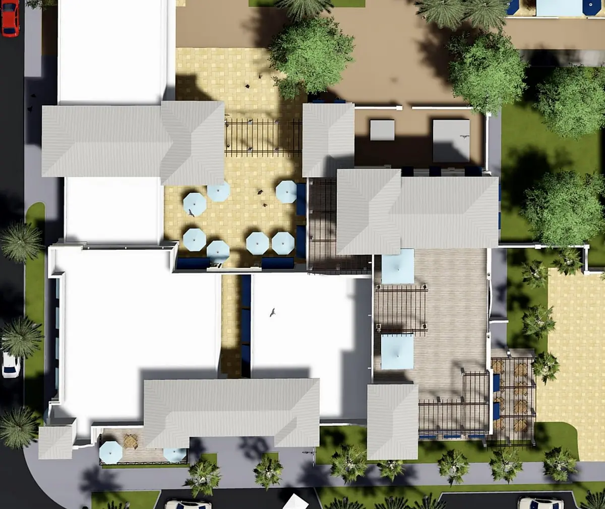 Aerial view of a property layout with buildings, courtyard, tables, and landscaped areas