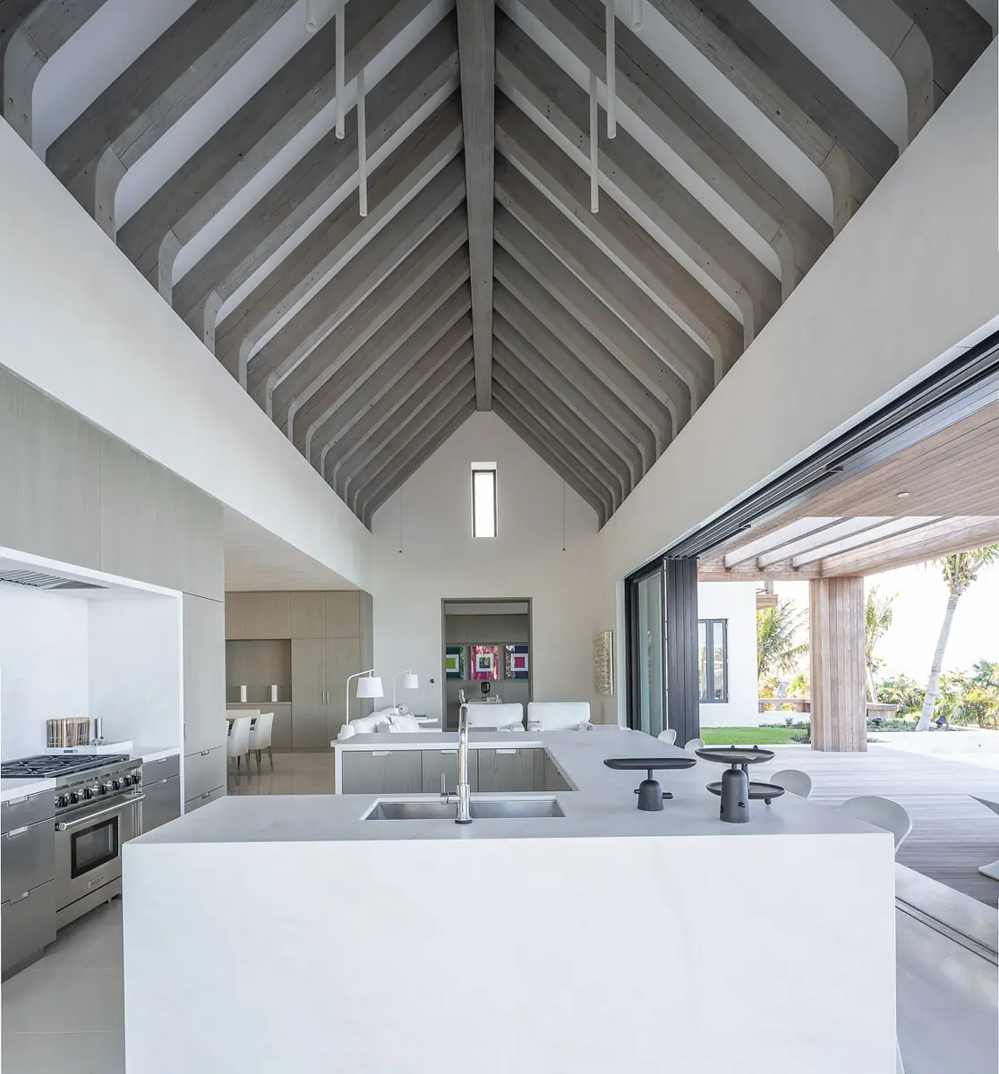 Kitchen with island, stainless steel appliances, light cabinetry, vaulted ceiling, and large sliding glass doors