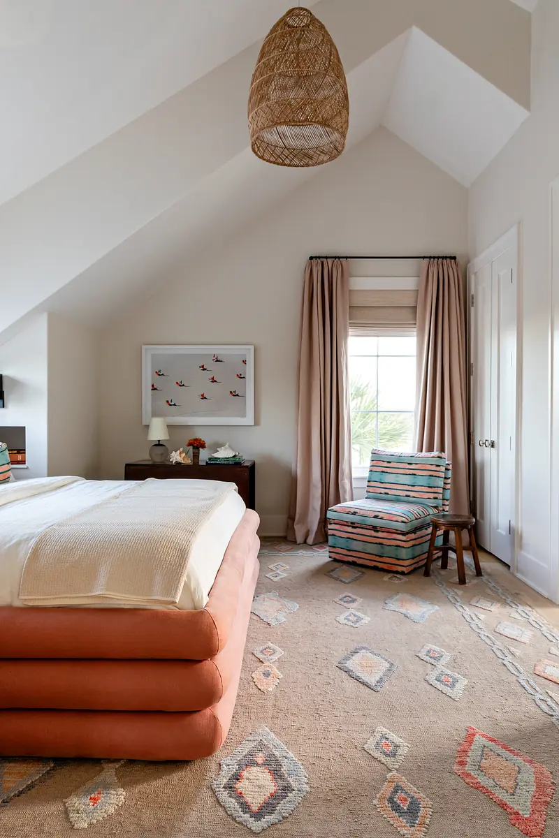 Bedroom with stacked bed, nightstand, striped chair, patterned rug, and bird motif painting.