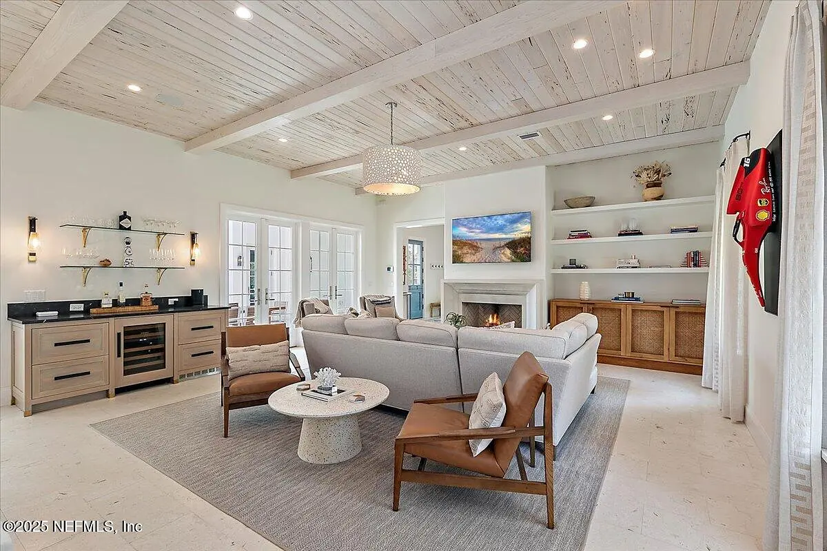 Living room with gray sectional sofa, brown armchairs, round coffee table, built-in shelves, and fireplace.