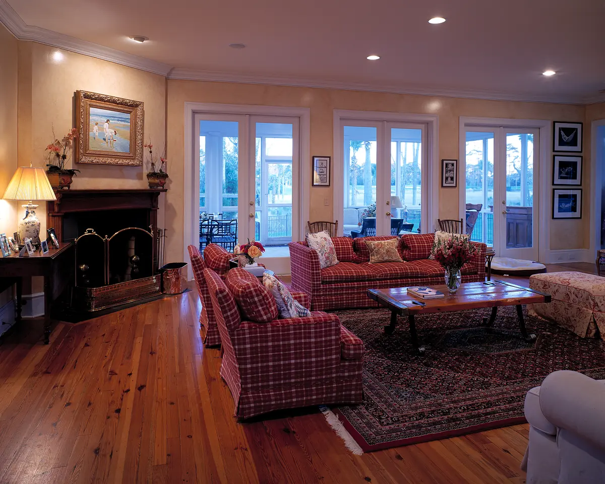 Living room with plaid sofas, coffee table, area rug, fireplace, and multiple doors to the outside.