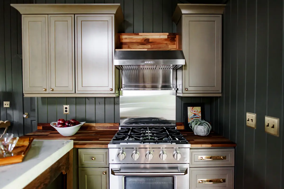 Kitchen with gray cabinetry, stainless steel range, wood countertops, and a bowl of red apples.