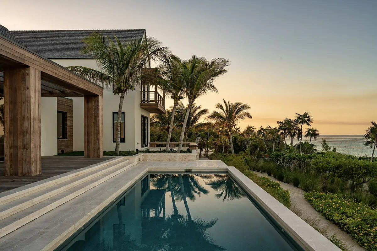 Exterior space with swimming pool, palm trees, wooden deck, and ocean view.
