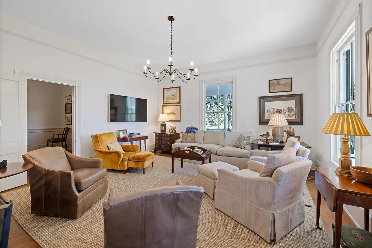 Living room with beige sofa, yellow and brown armchairs, television, framed artwork, and area rug.