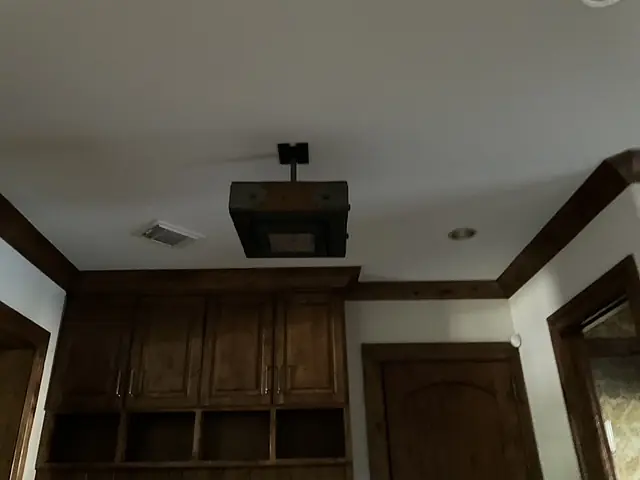 Ceiling with trim, mounted fixture, wooden cabinet, and door in a small room or alcove.
