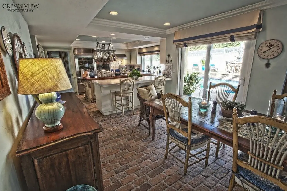 Dining room with a wooden table, six chairs, sideboard, lamp, and open kitchen area with patio views.