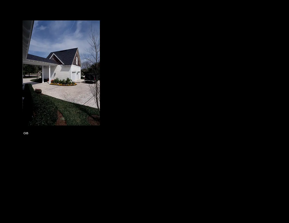 Exterior view of a house with gabled roof, white siding, stone pathway, and landscaped garden with yellow flowers.