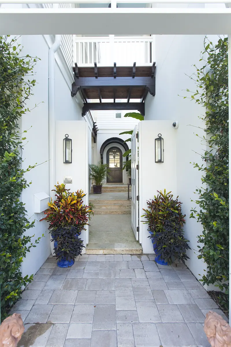 Foyer with stone pathway, arched doorway, potted plants, and wooden beams overhead.