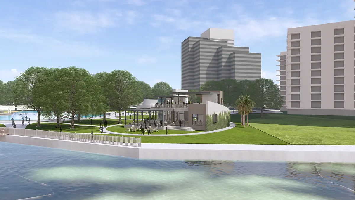 Modern building with glass windows, circular design, greenery, and palm trees in front of a body of water.