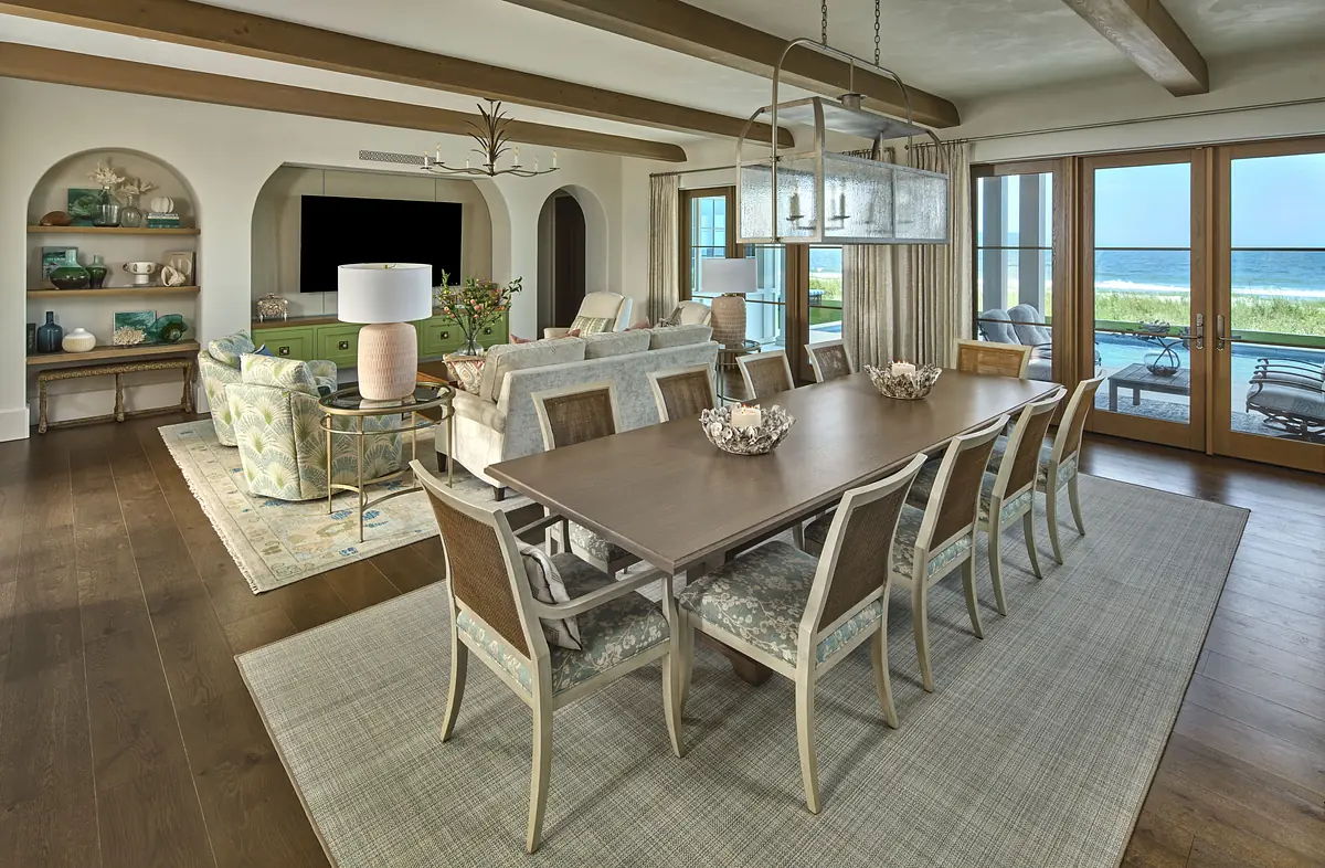 Dining room with wooden table, eight chairs, area rug, sideboard, and glass sliding door to outdoor view.
