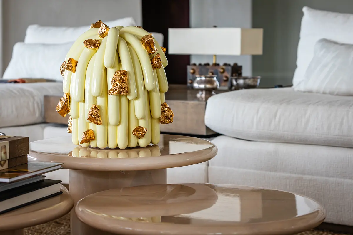 Living room with light sofa, round side tables, decorative object, and stacked books.