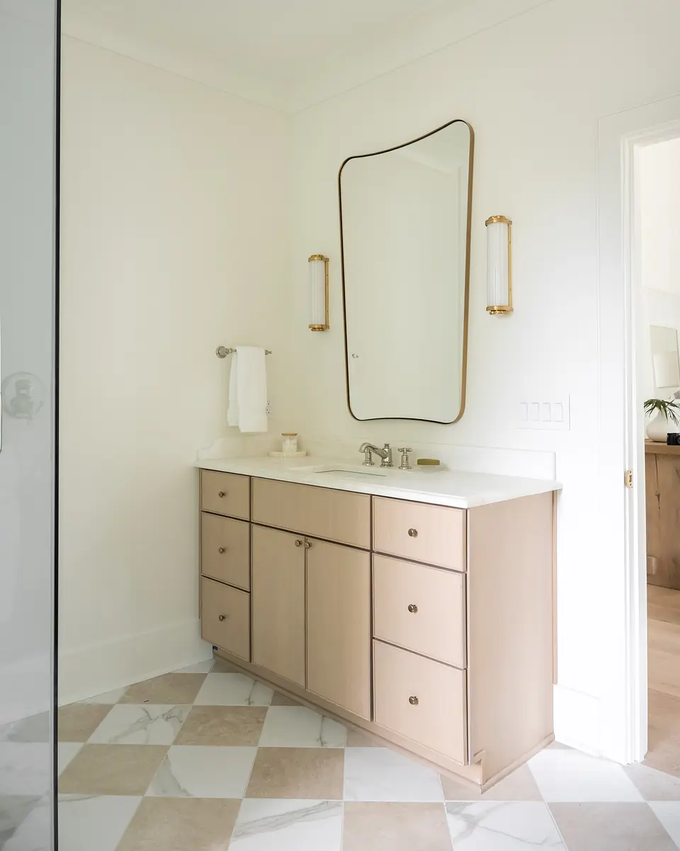 Bathroom with beige vanity, white countertop, modern mirror, patterned tile floor, and glass shower.