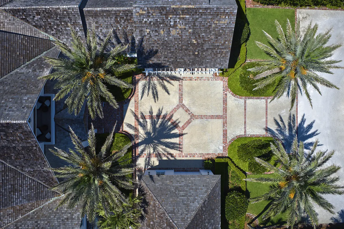 Exterior front view with paved area, palm trees, and landscaped garden.