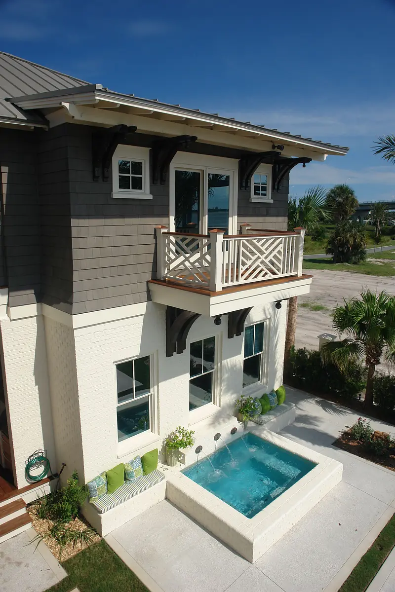 Exterior view with plunge pool, three large windows, balcony, and landscaping with plants.