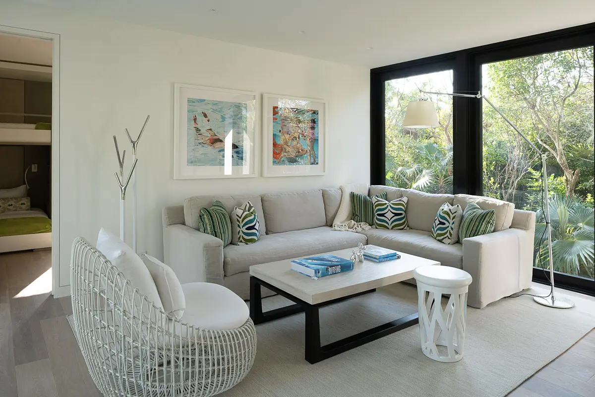 Living room with large sectional sofa, coffee table, accent chairs, wall art, and floor lamp with large windows.