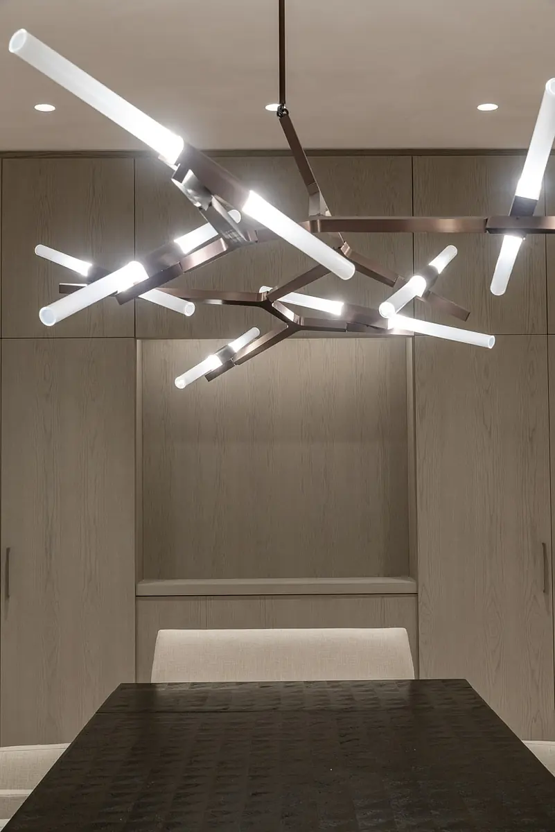 Dining room with dark wood table, upholstered chairs, and modern geometric chandelier.
