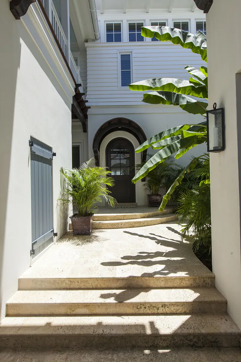 Exterior front area with stone pathway, wooden door, planters, and mounted light fixture