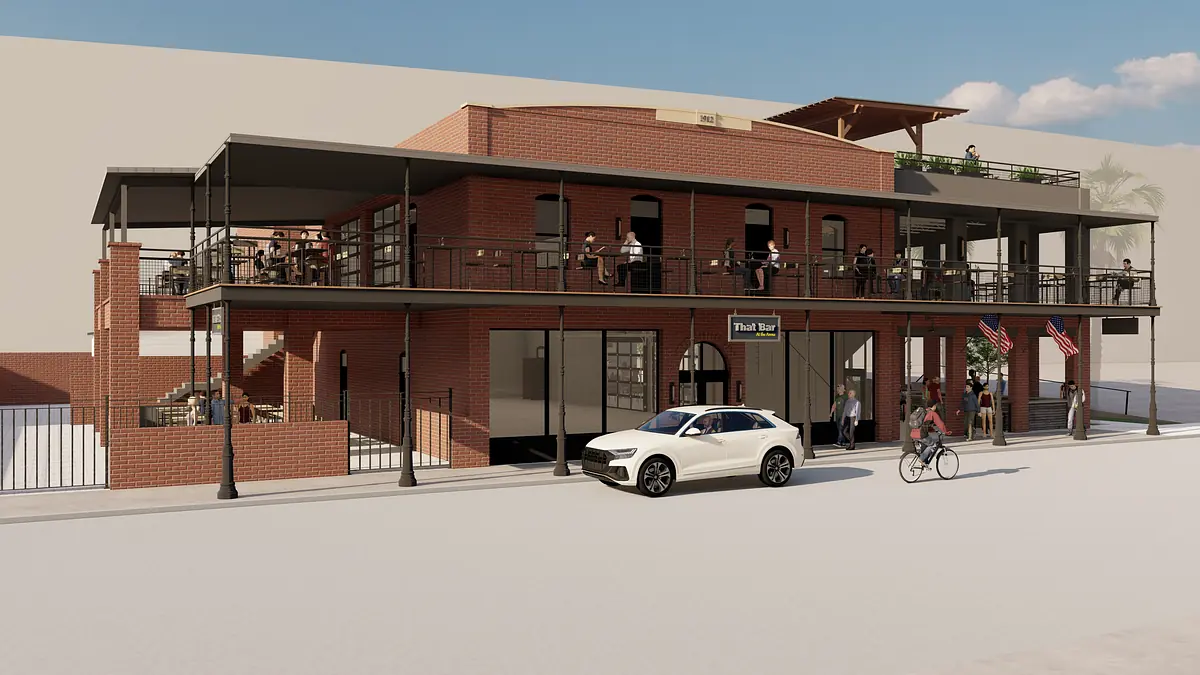Exterior view of a two-story brick building with balconies, terrace, and activity around it.