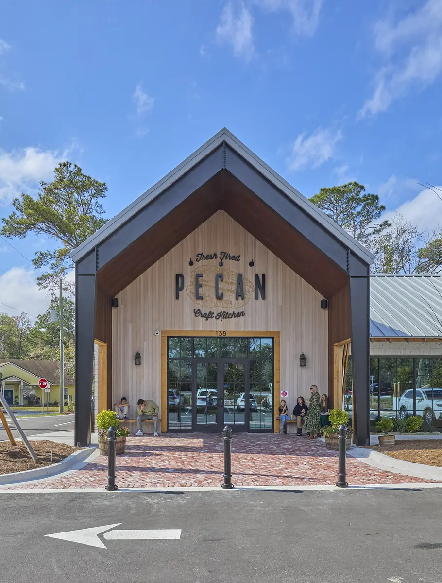 Front exterior with A-frame roof, glass entrance, brick pathway, and landscaped areas.