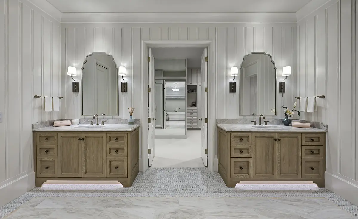 Bathroom with two vanities, marble countertops, large mirrors, paneled walls, and tiled flooring.