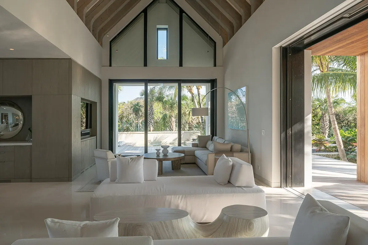 Living room with light sofas, round coffee table, large windows, and access to an outdoor area