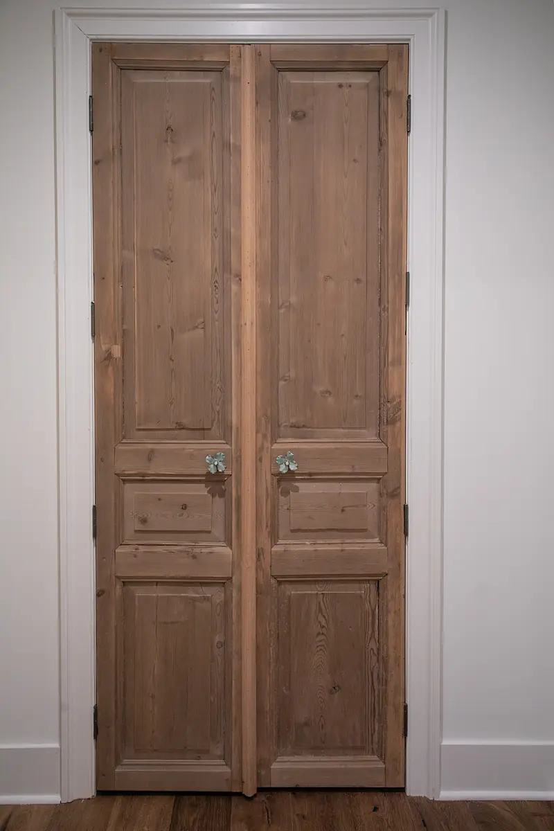 Double wooden doors with panel design, metal handles, and hardwood flooring.