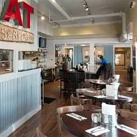 Dining room with wooden tables, chairs, service counter, wall signage, and large windows.