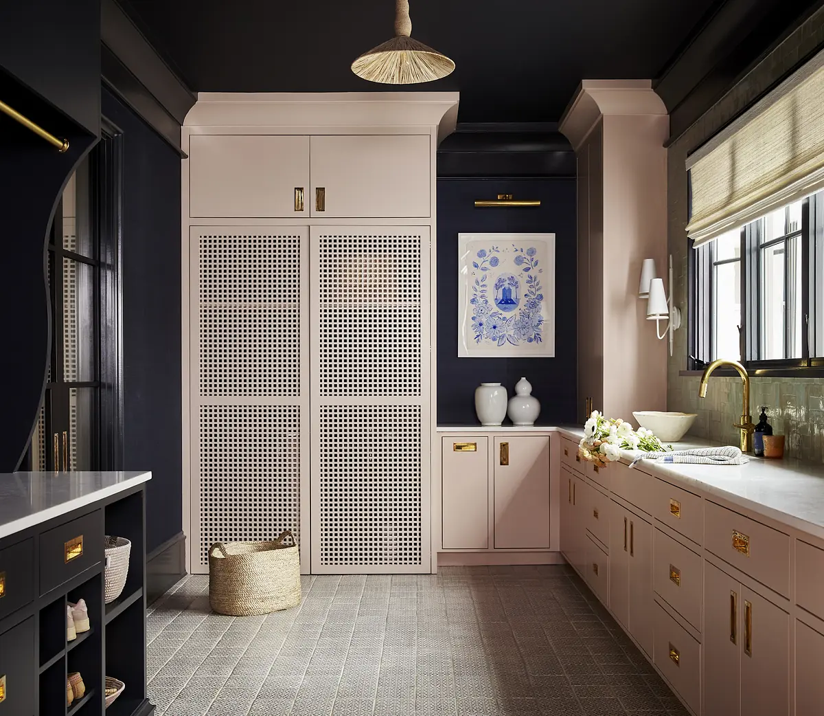 Kitchen with dark ceiling, light cabinetry, artwork, countertop, brass faucet, and woven basket.