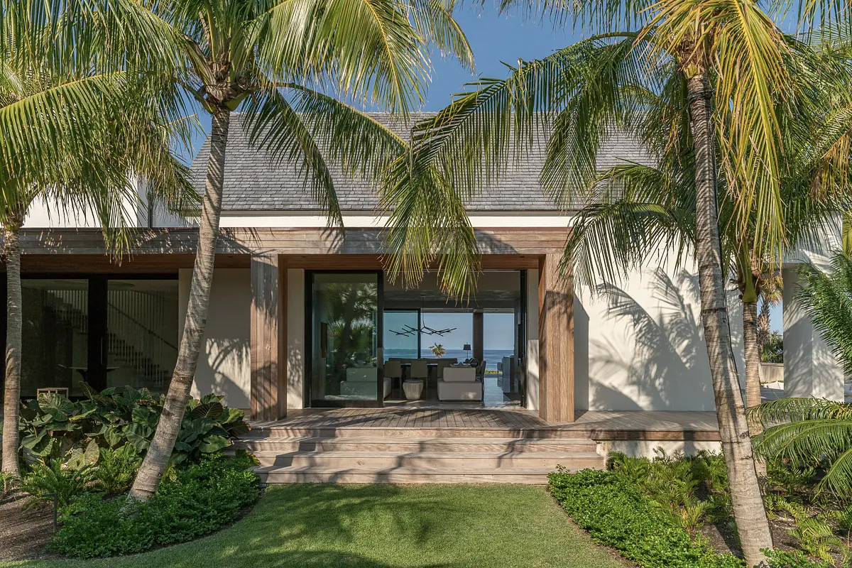 Exterior front view of a house with staircase, large windows, wood accents, and palm trees.