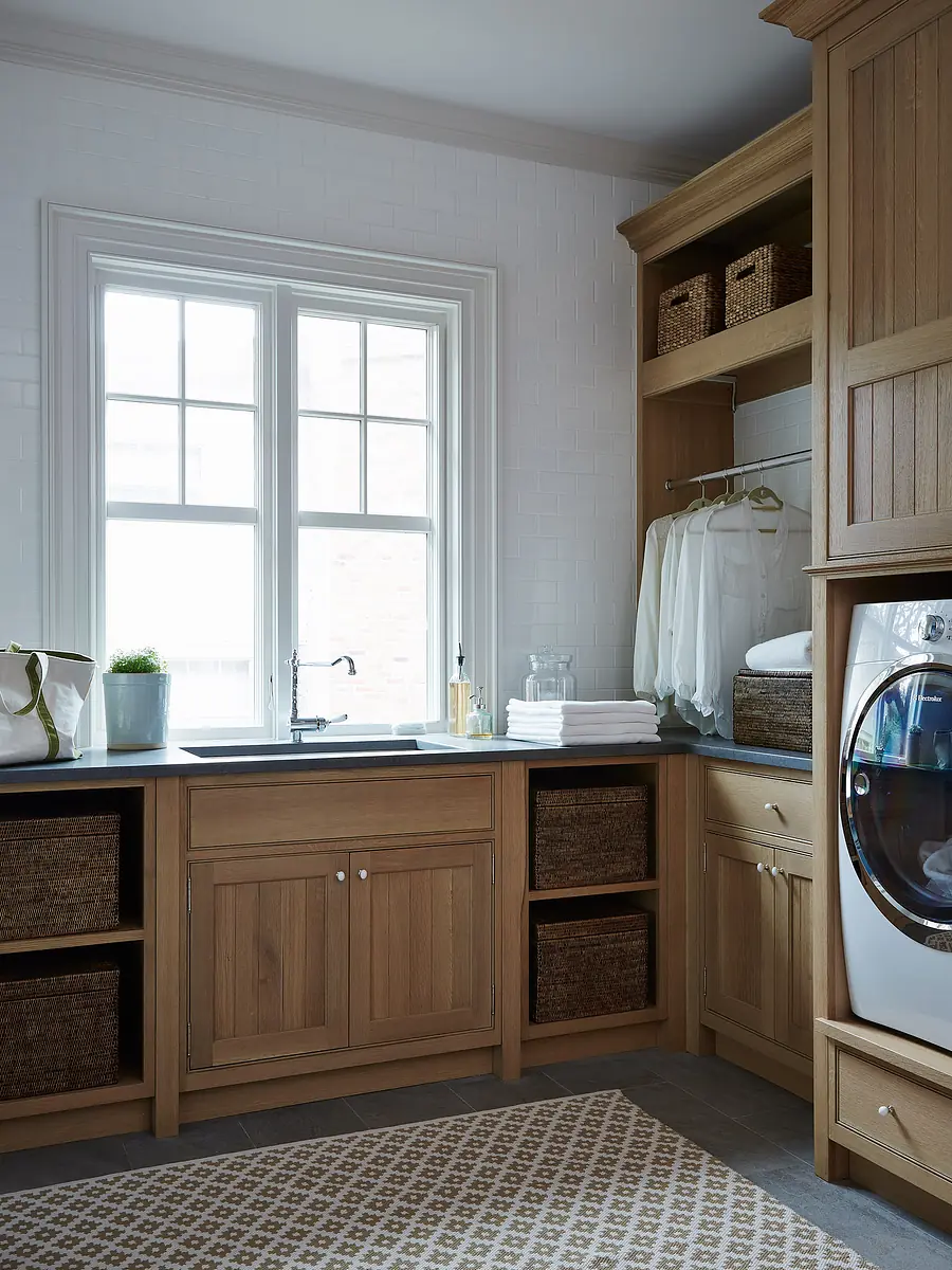 Laundry room with washing machine, wooden cabinetry, gray countertop, baskets, towels, and patterned rug