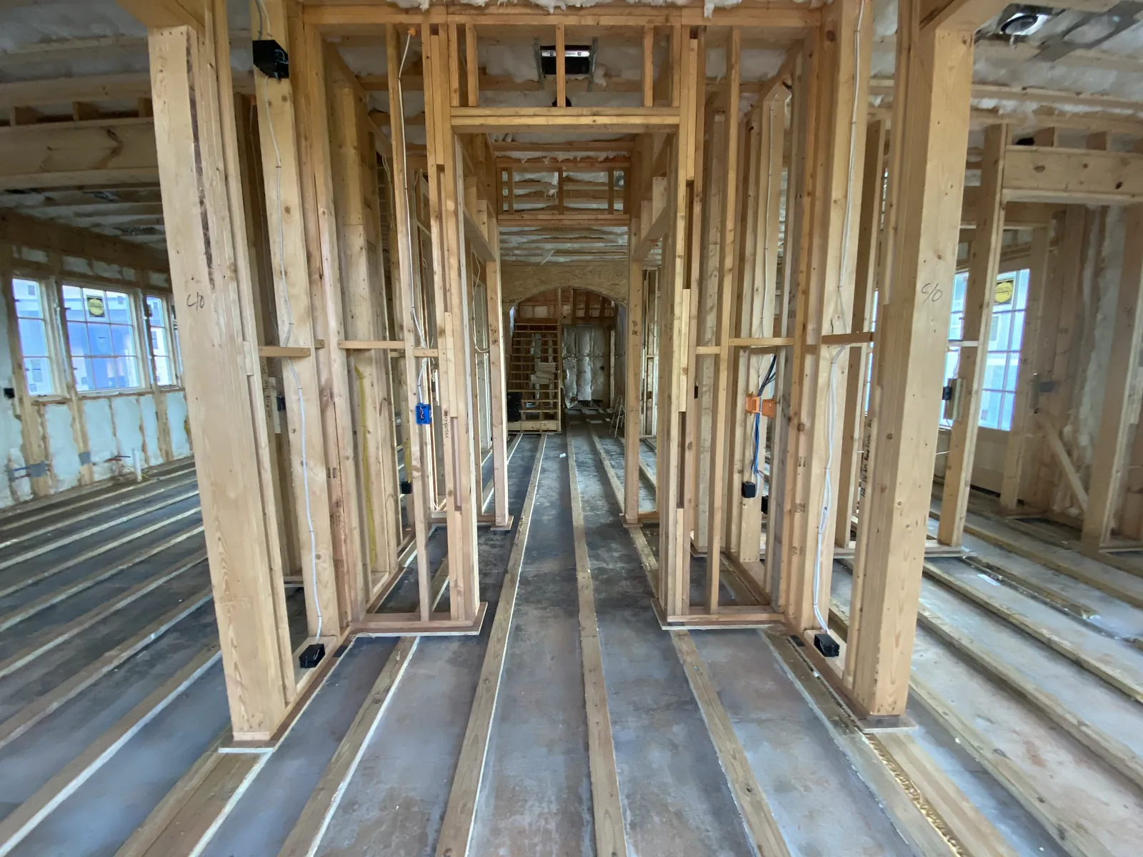 Under-construction space with exposed wooden framing and stripped floors.