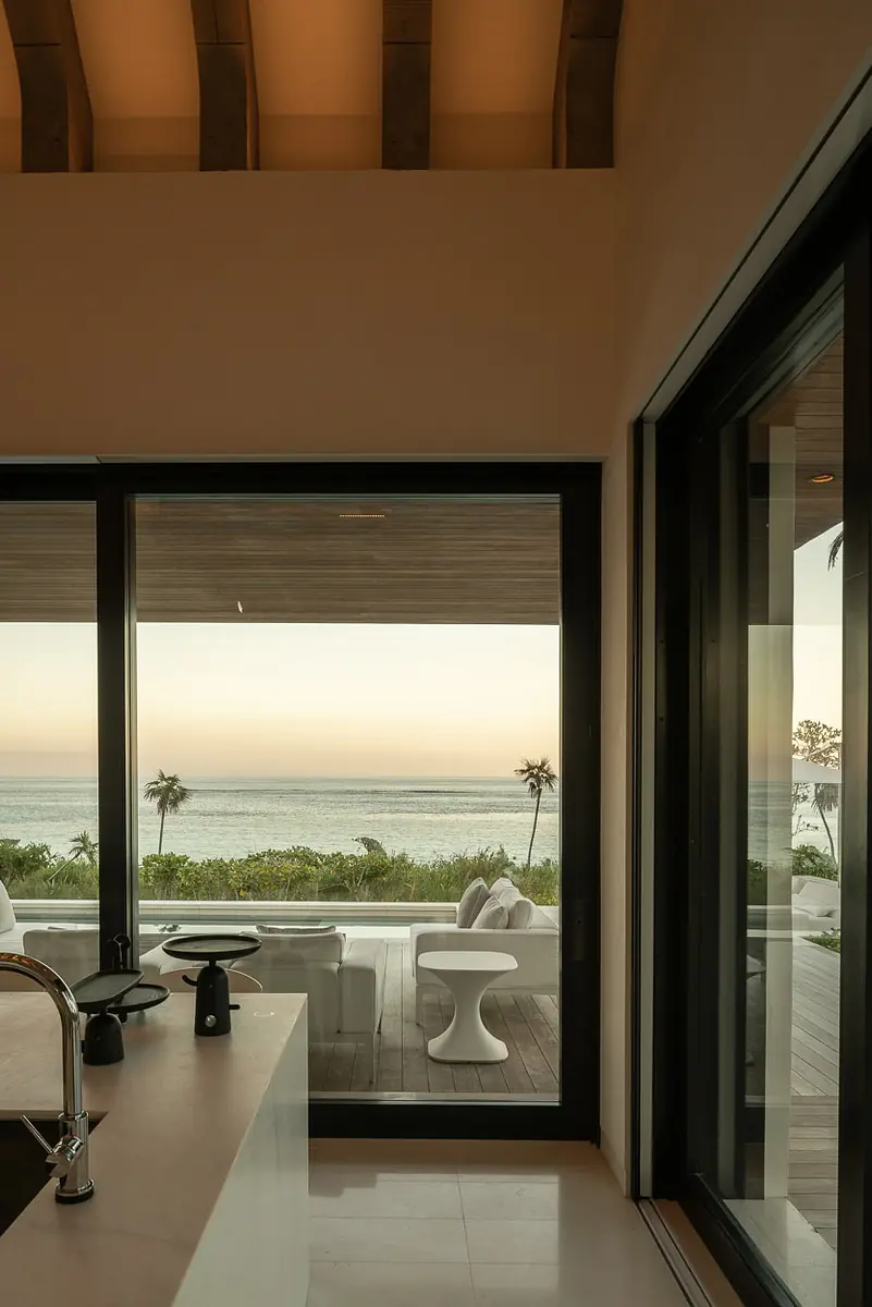 Kitchen with countertop, sink, large windows, and wooden beams, offering a view of the sea.