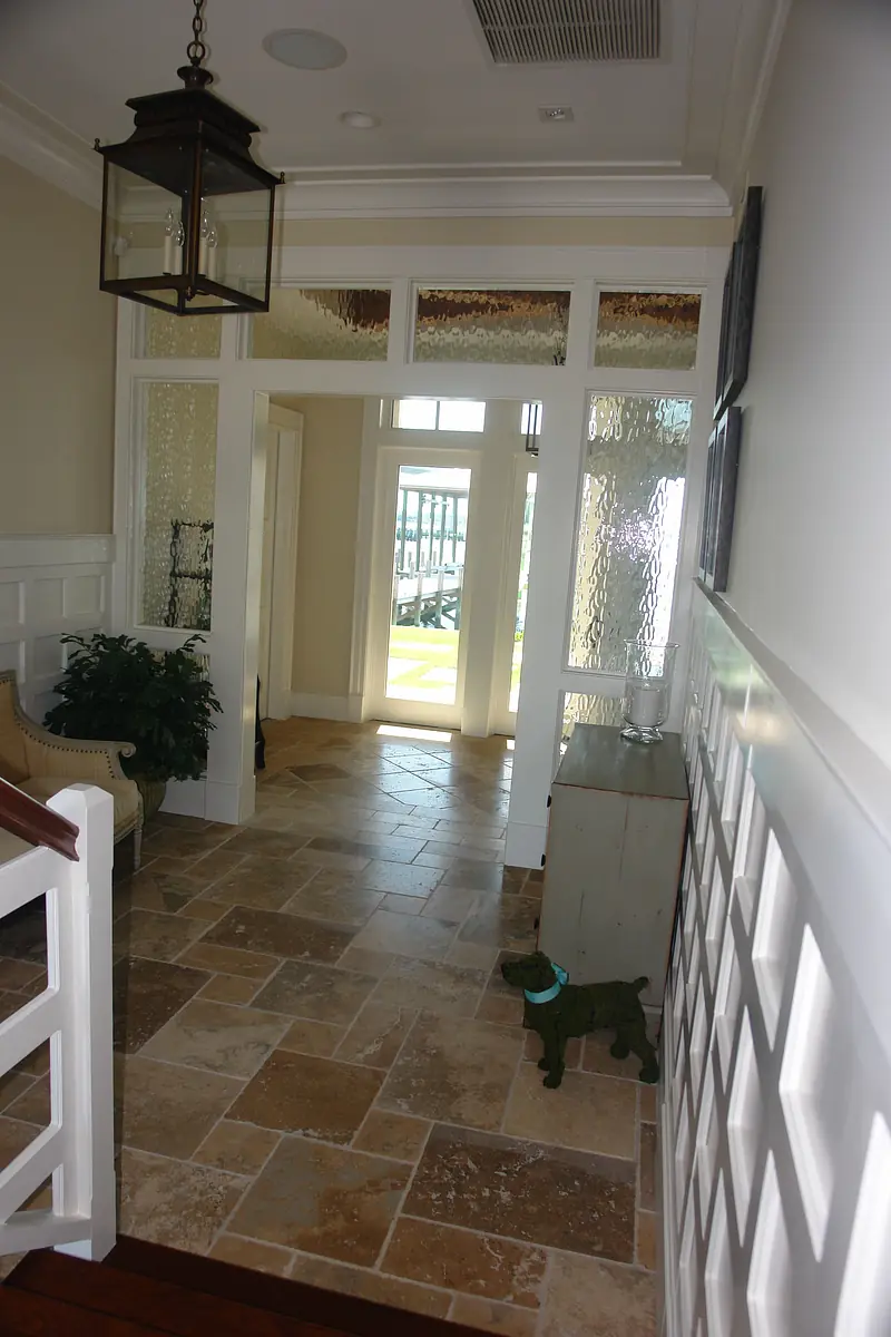 Hallway with stone flooring, white wainscoting, glass doors, a lantern light fixture, and decorative elements.