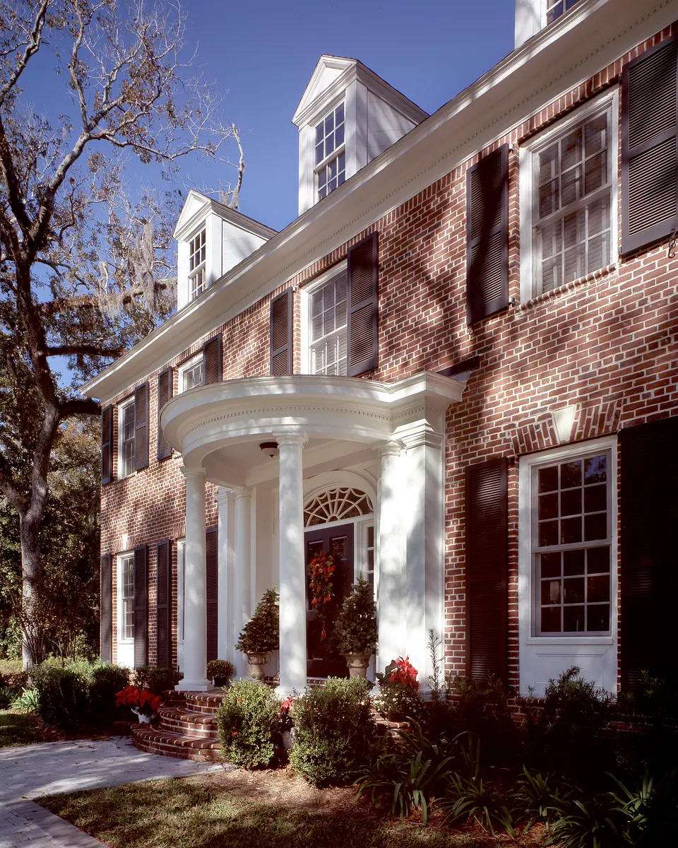 Front exterior with brick façade, white columns, multiple windows, and landscaped garden