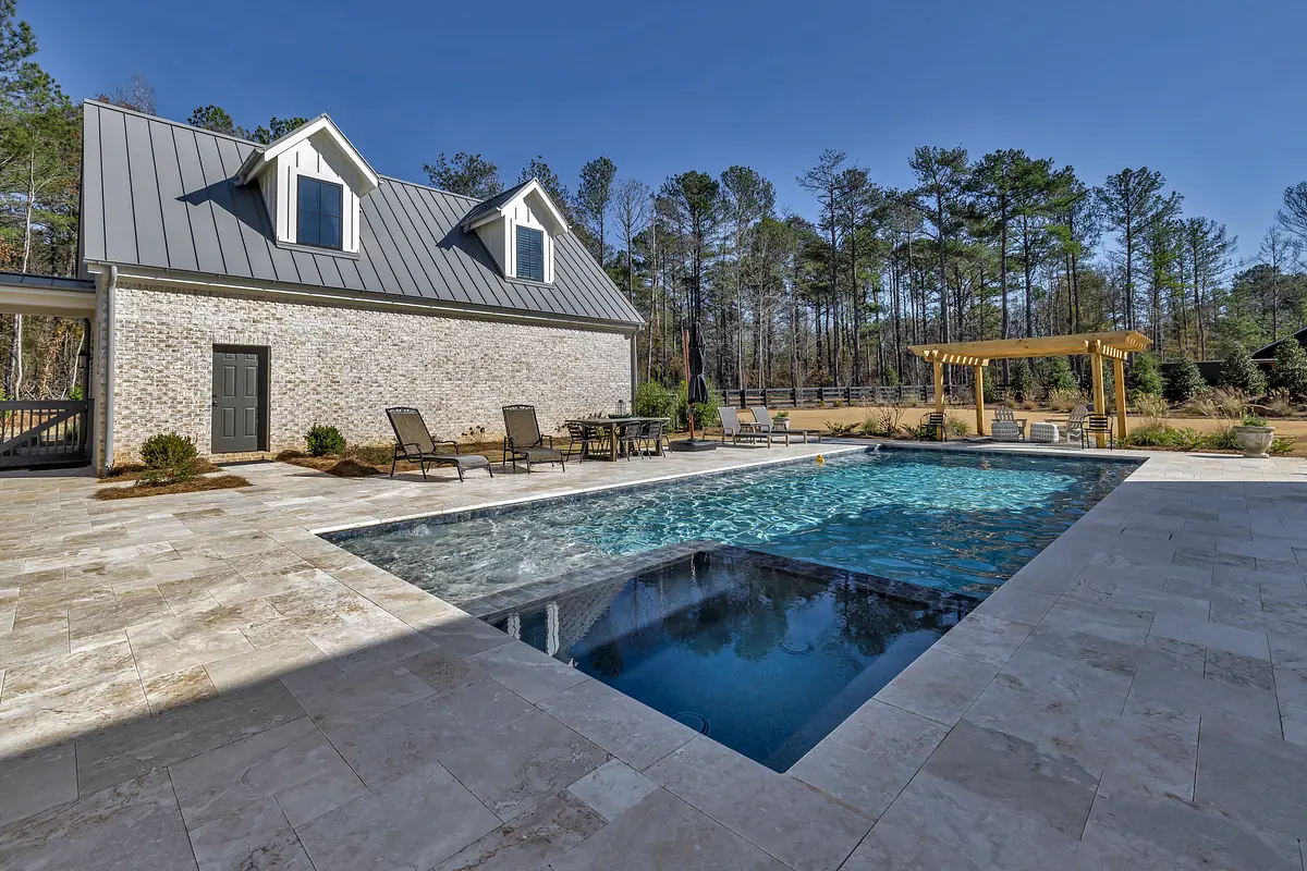 Exterior rear with swimming pool, chaise lounges, pergola, and stone tiles