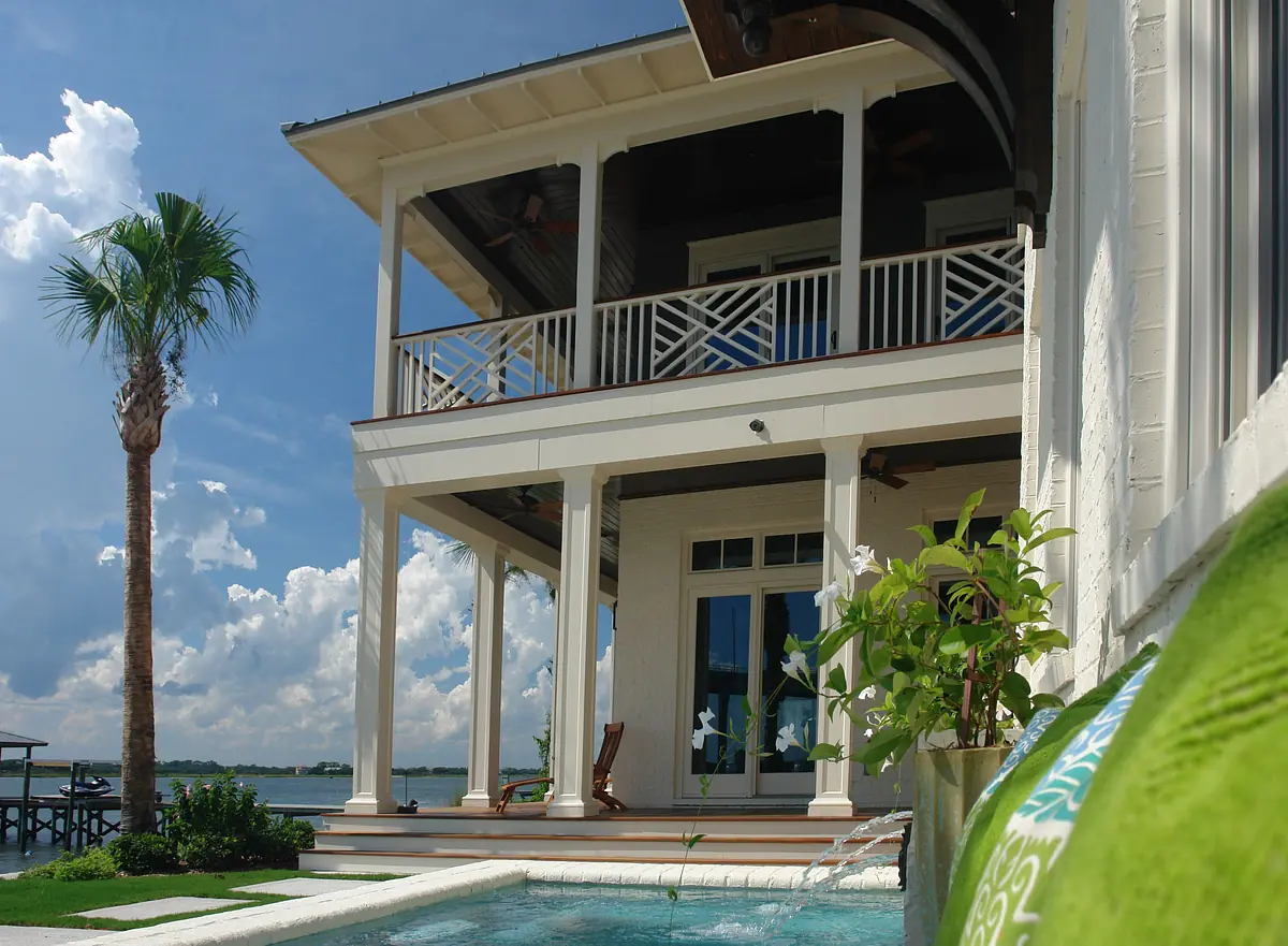 Exterior rear view of house with porch, palm tree, pool, and large windows