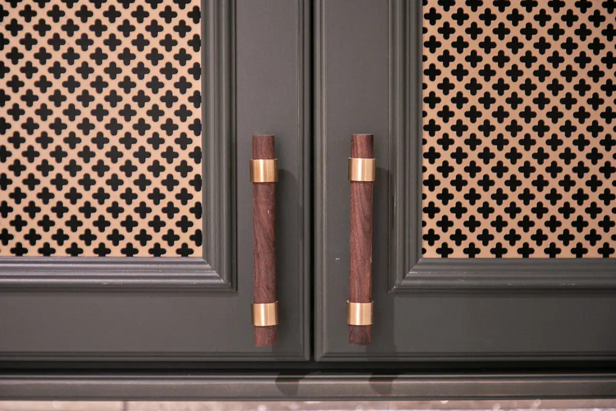 Kitchen cabinet doors with dark green panels, gold hardware, and cane webbing inserts.