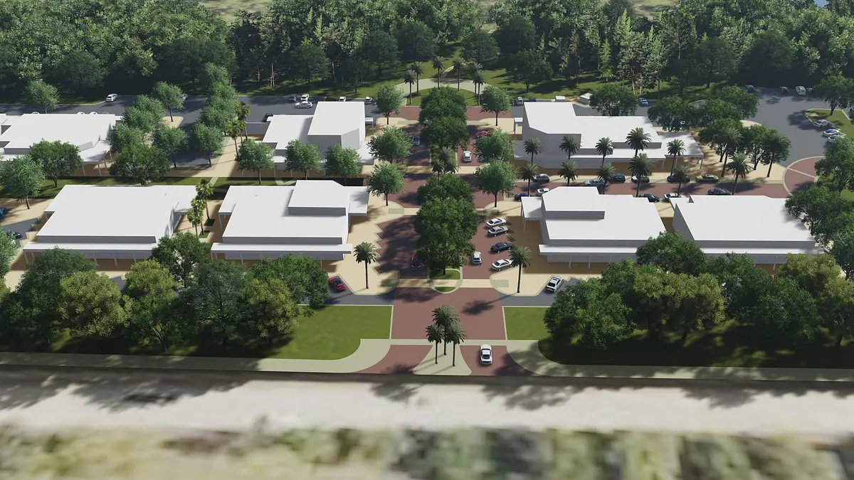 Aerial view of residential community with buildings, roads, green spaces, and palm trees.