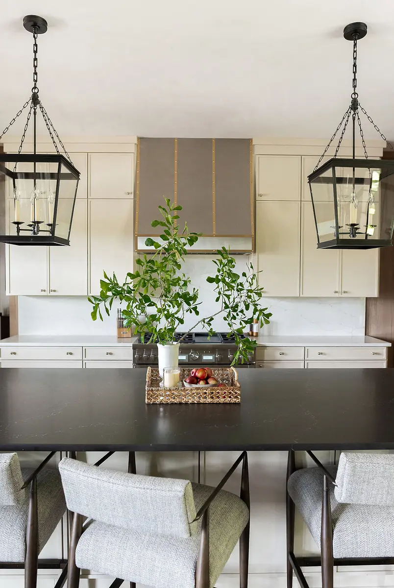 Kitchen with island, bar stools, gas stove, cabinetry, marble countertops, and pendant lights.