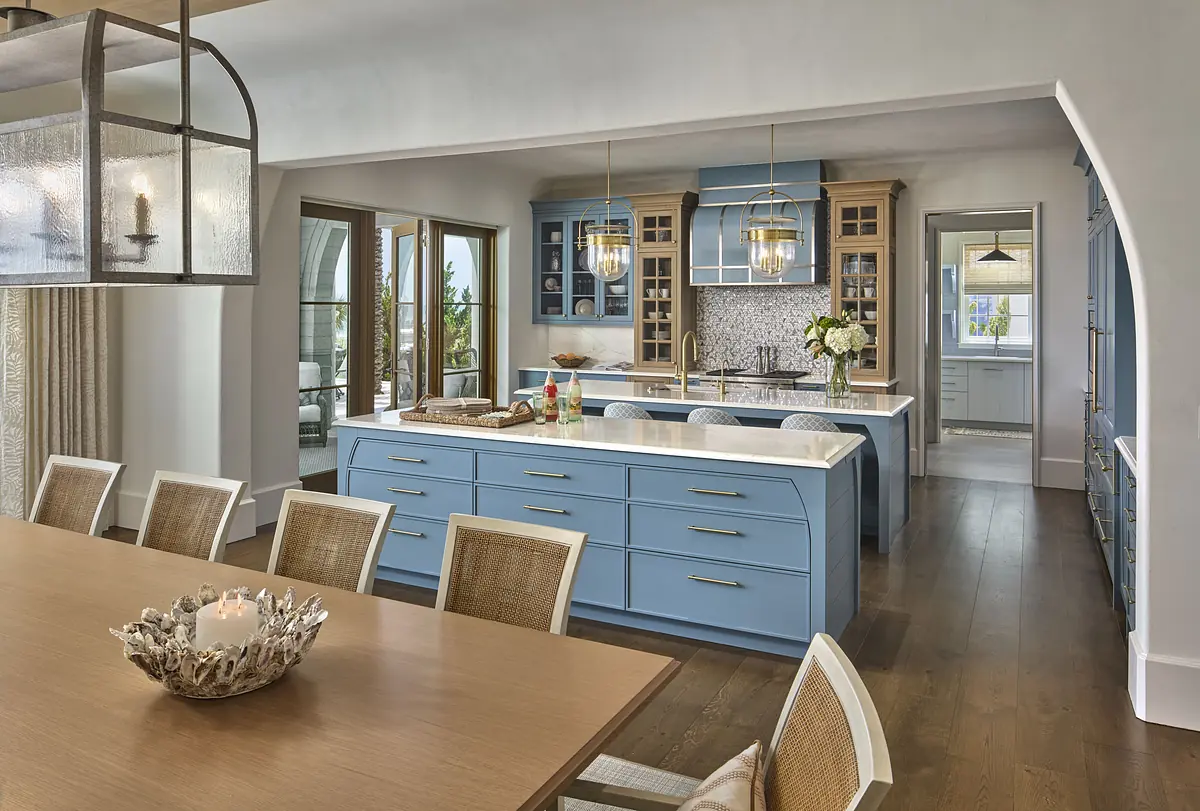 Kitchen with blue cabinetry, white countertops, central island, and dining table with natural light.