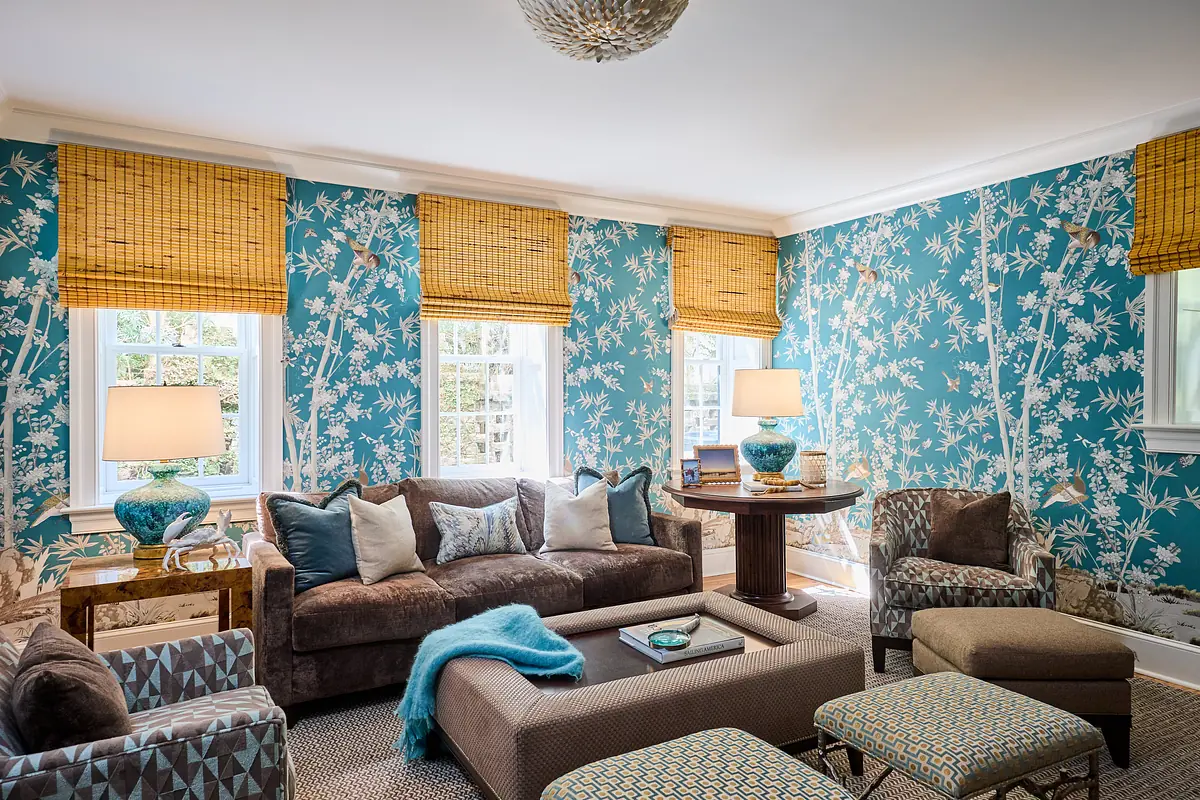 Living room with brown sectional sofa, patterned armchairs, turquoise wallpaper, and area rug.