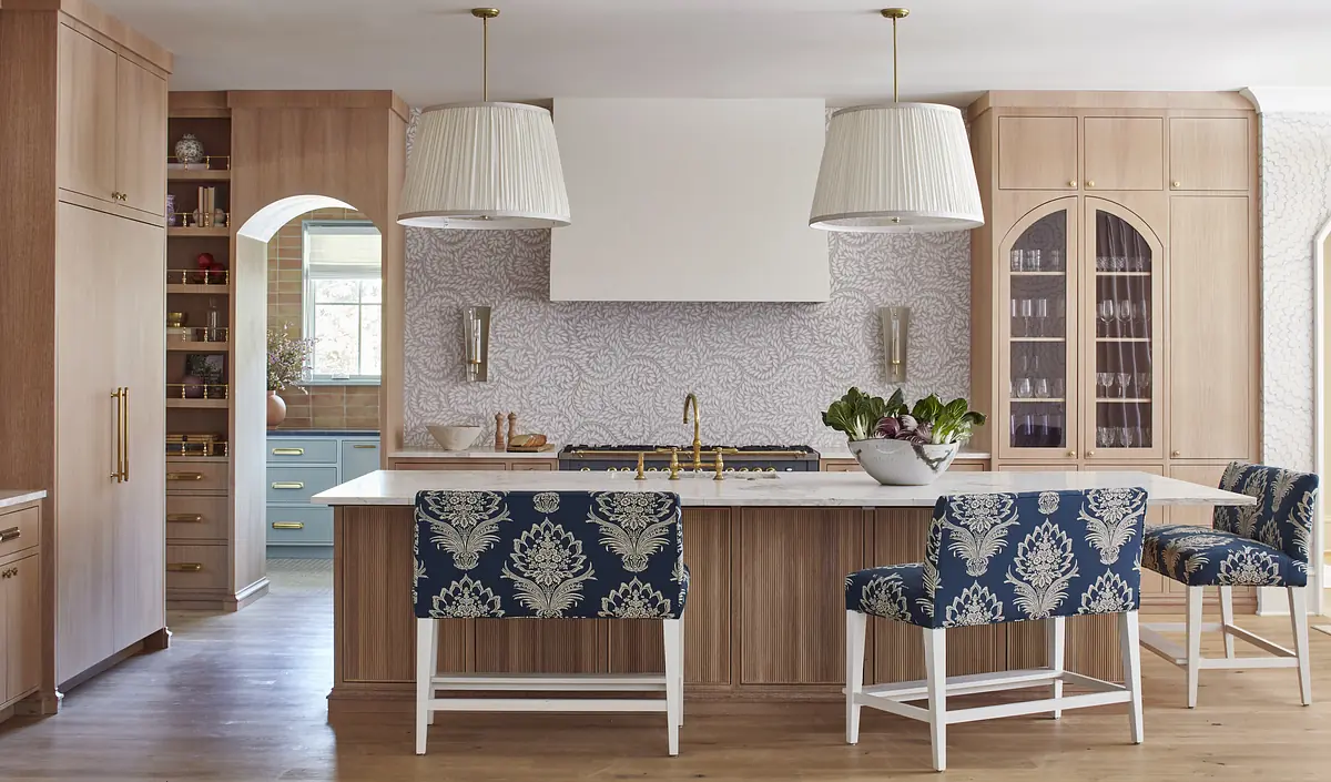 Kitchen with central island, patterned bar stools, wooden cabinetry, and decorative backsplash.