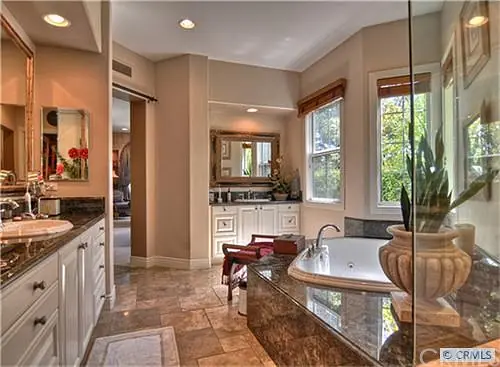 Bathroom with freestanding tub, dual sink vanity, separate shower, large mirrors, and tile flooring.