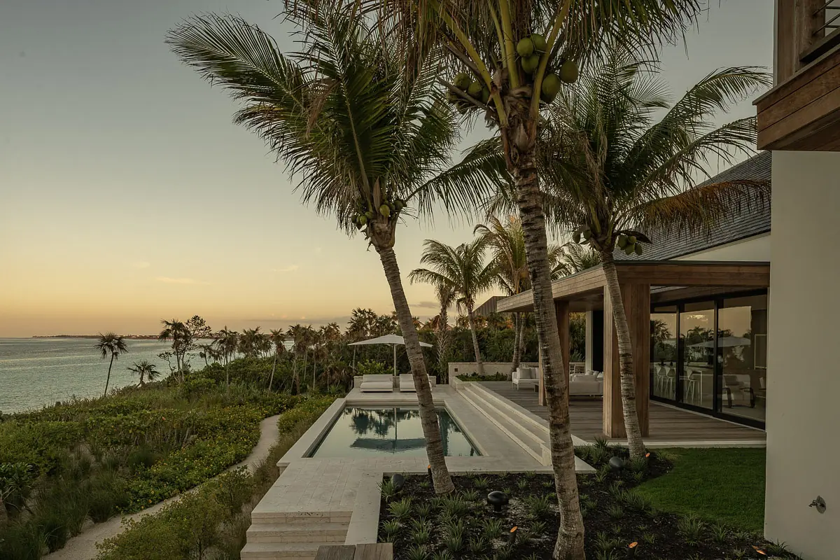 Exterior space with swimming pool, wooden deck, lounge chairs, palm trees, and ocean view
