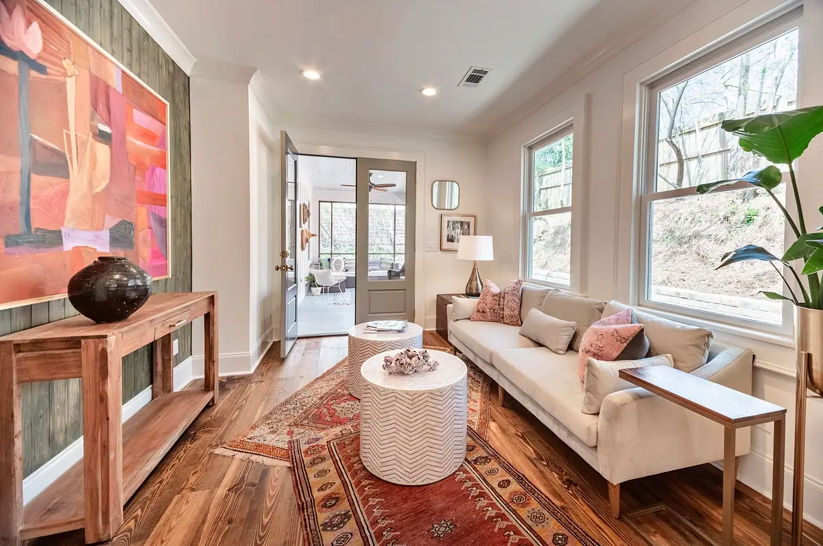 Living room with white sofa, circular coffee table, area rug, and large windows.