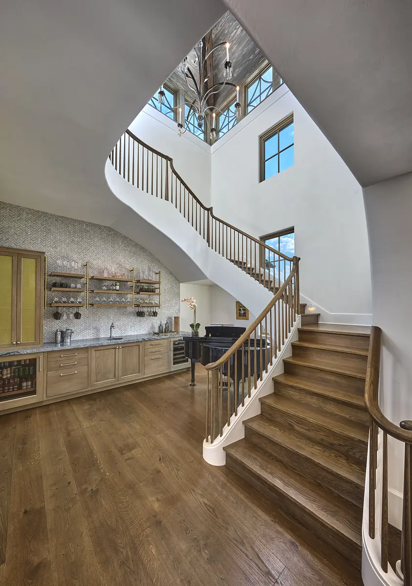 Foyer with curved staircase, cabinetry, textured wall, and large windows for natural light.