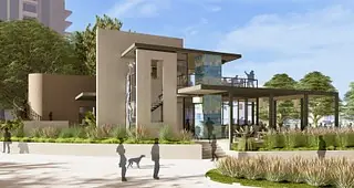 Exterior view of a modern building with glass windows, landscaping, and a walkway.